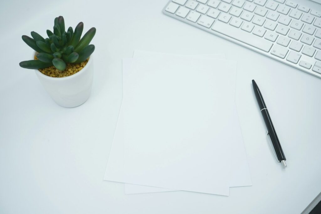 Blank sheets of paper and a pen on a desk, ready for rewriting an artist statement