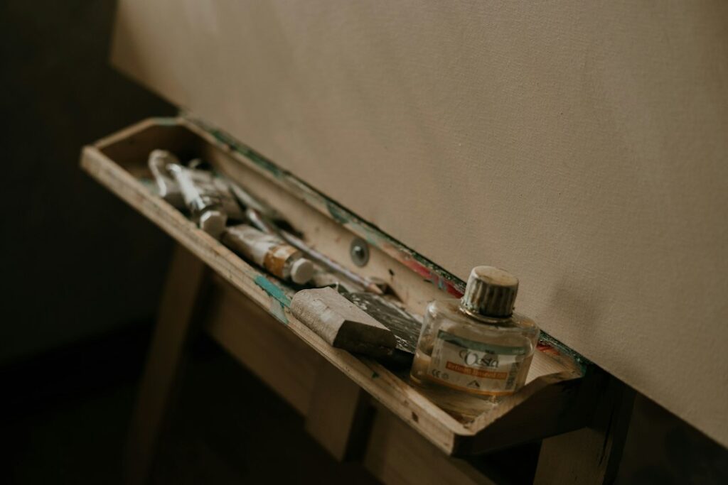 Blank canvas on a wooden easel with paint brushes and art supplies in a painter's studio