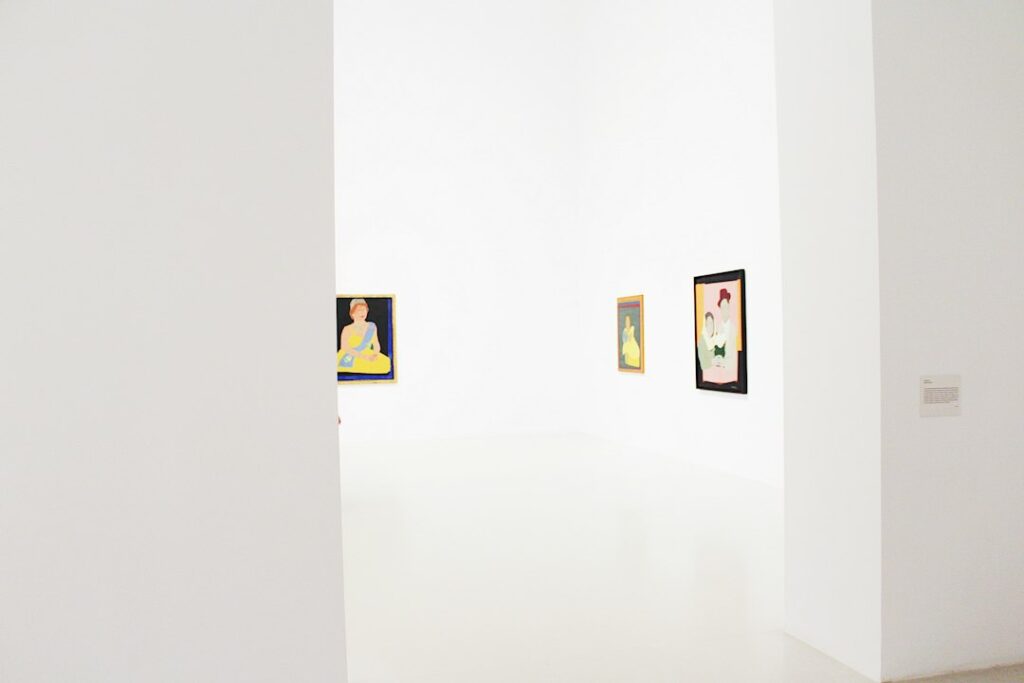 Paintings hanging on the white walls of an empty art gallery