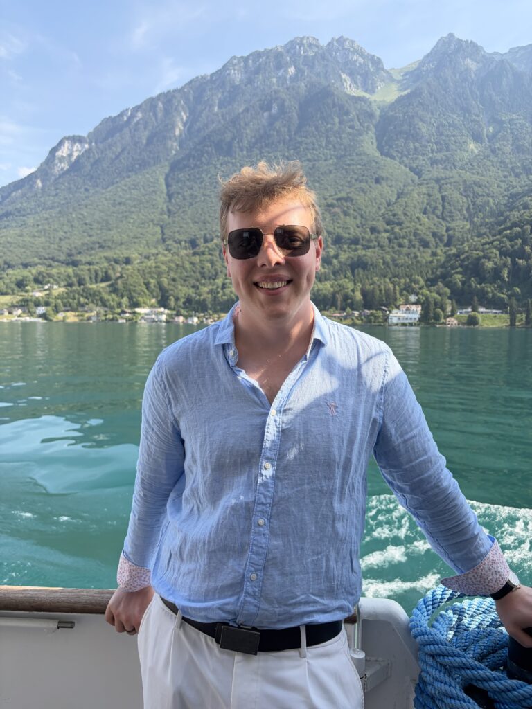 James Carter on a boat trip on Lake Geneva with mountains behind