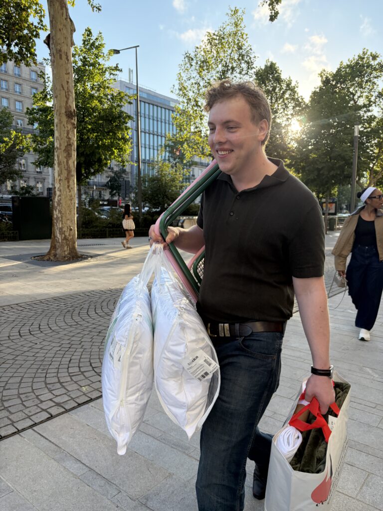 James Carter carrying pillows along a street in Paris