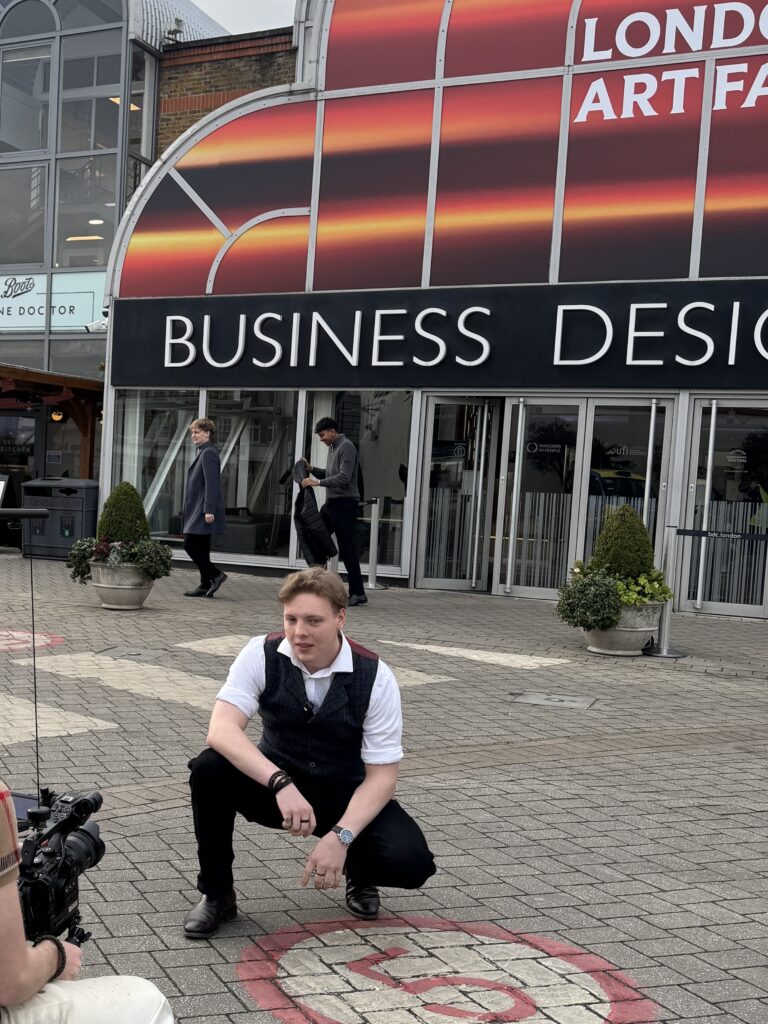 James Carter crouching outside London Art Fair at the Business Design Centre, Islington
