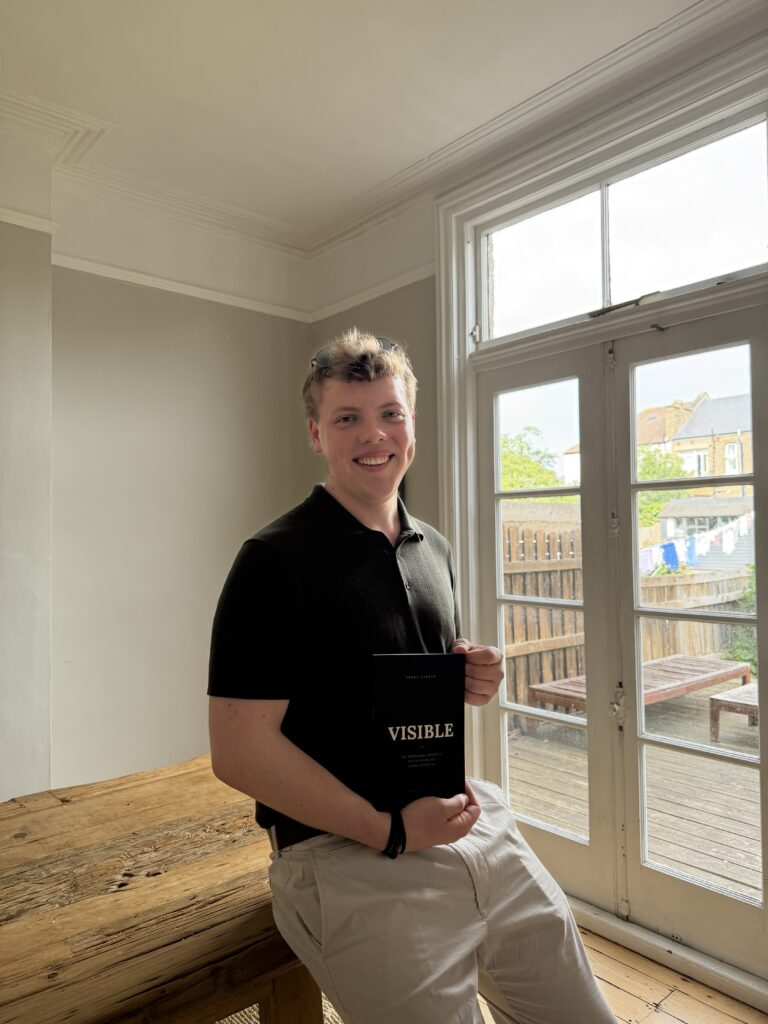 James Carter holding a copy of his book VISIBLE, a field guide for emerging artists