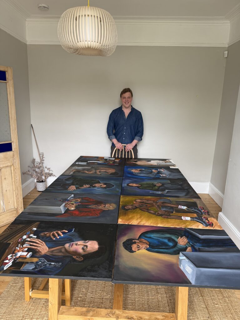 James Carter with oil portrait paintings laid out on a table