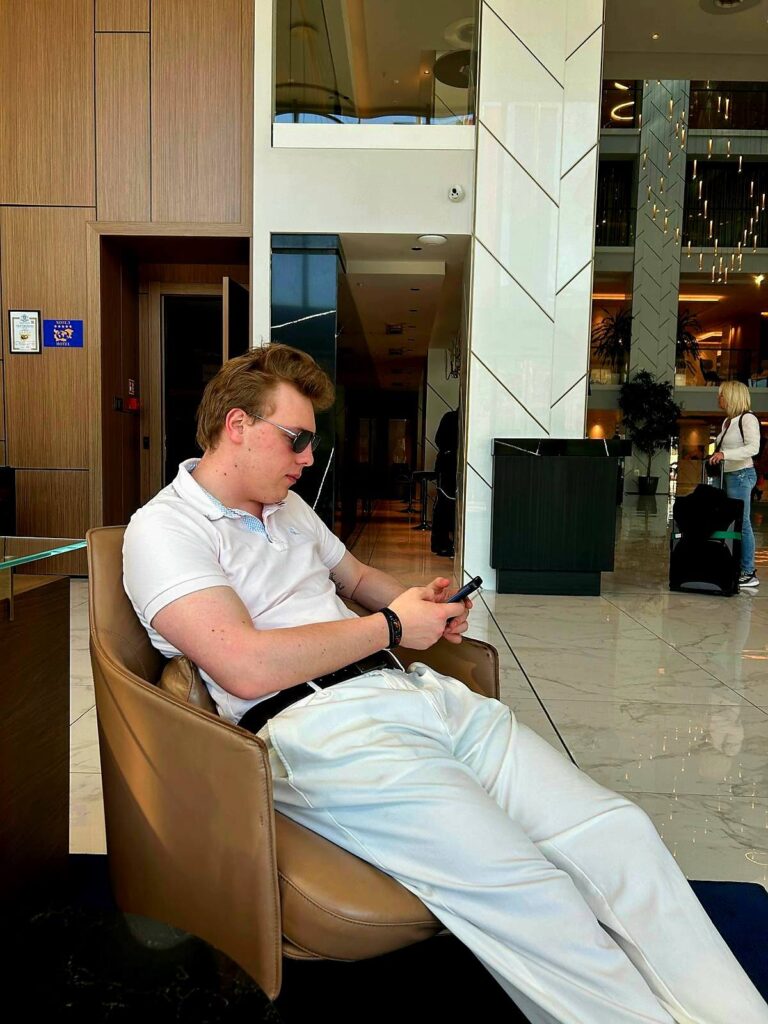 James Carter relaxing in a hotel lobby in white trousers
