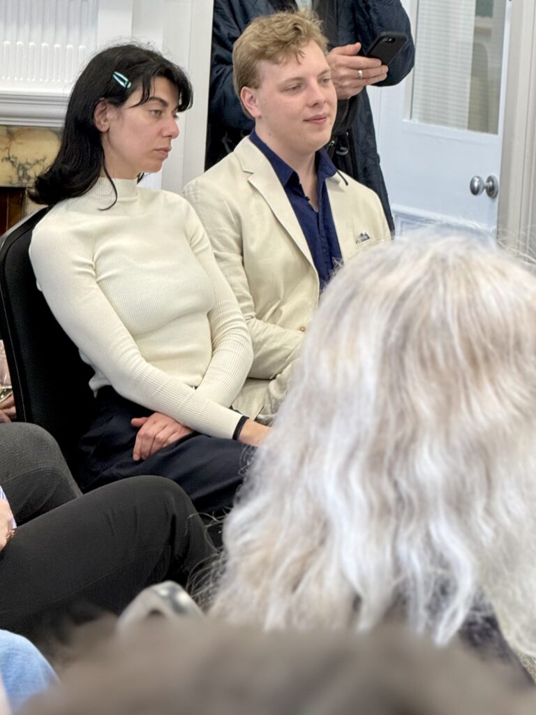 James Carter seated at a talk event in a cream suit