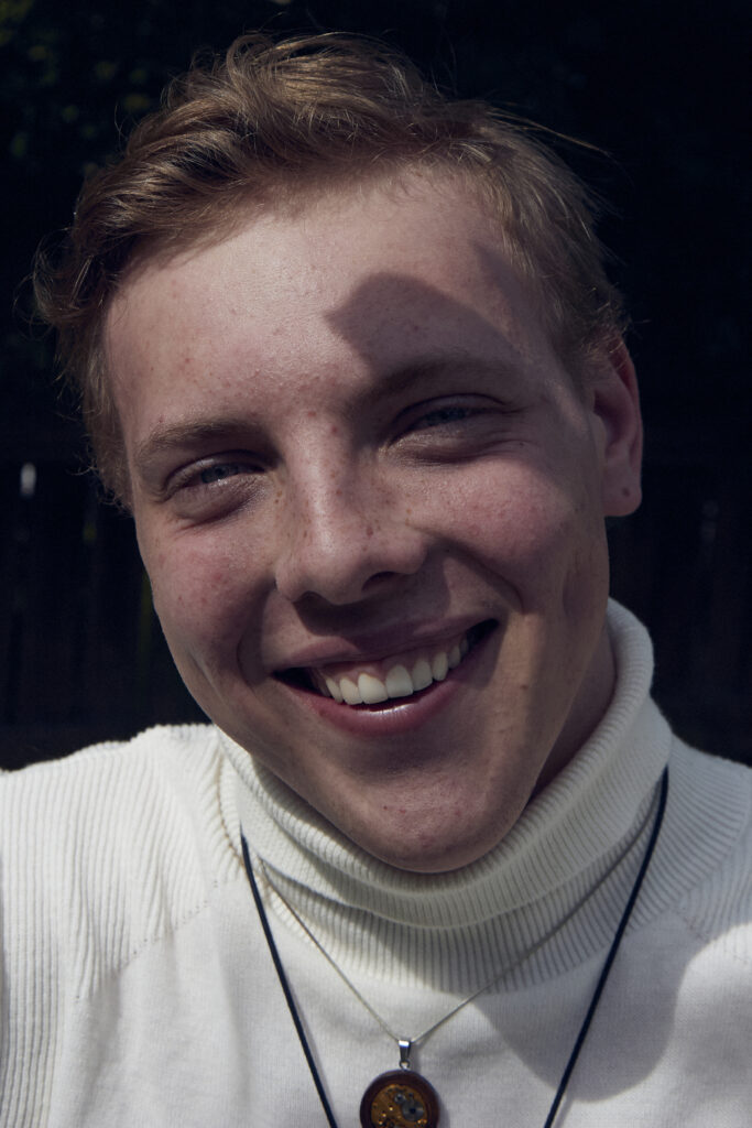 Close up of James Carter smiling in a white roll neck
