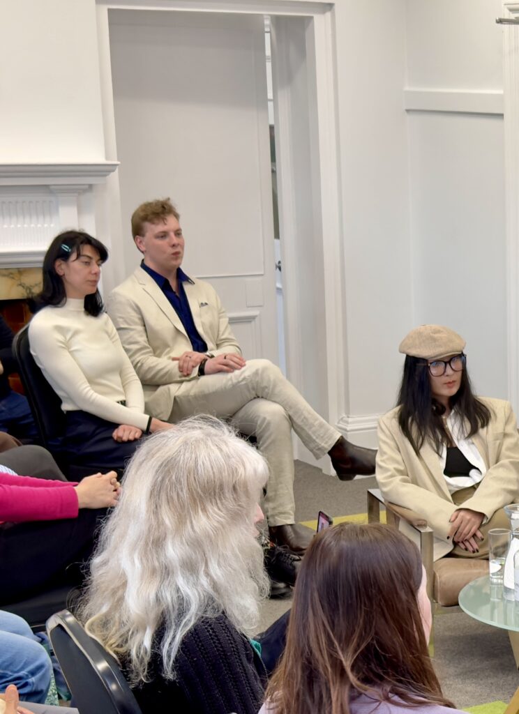 James Carter speaking at a panel talk in a cream suit