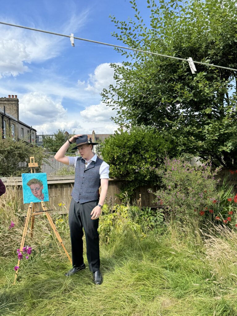 James Carter tipping his fedora beside a painting on an easel