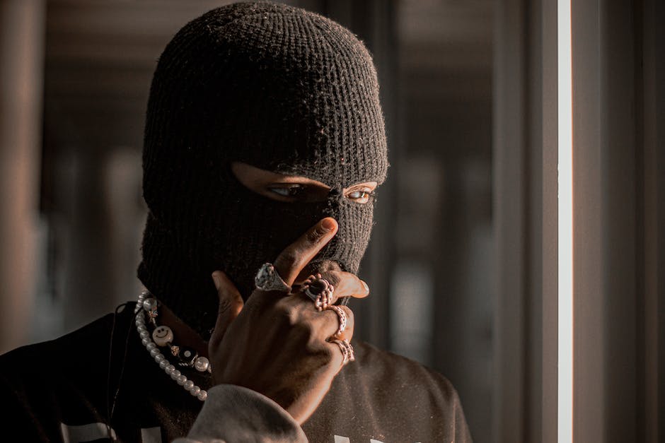 Image of a person wearing a black ski mask holding a painting, representing art theft.
